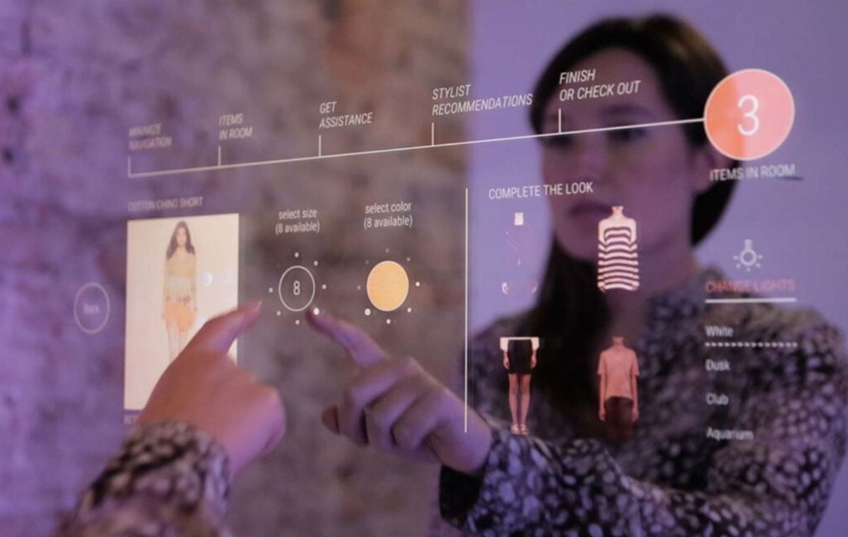 A woman engages with a smart retail touchscreen to shop for clothing