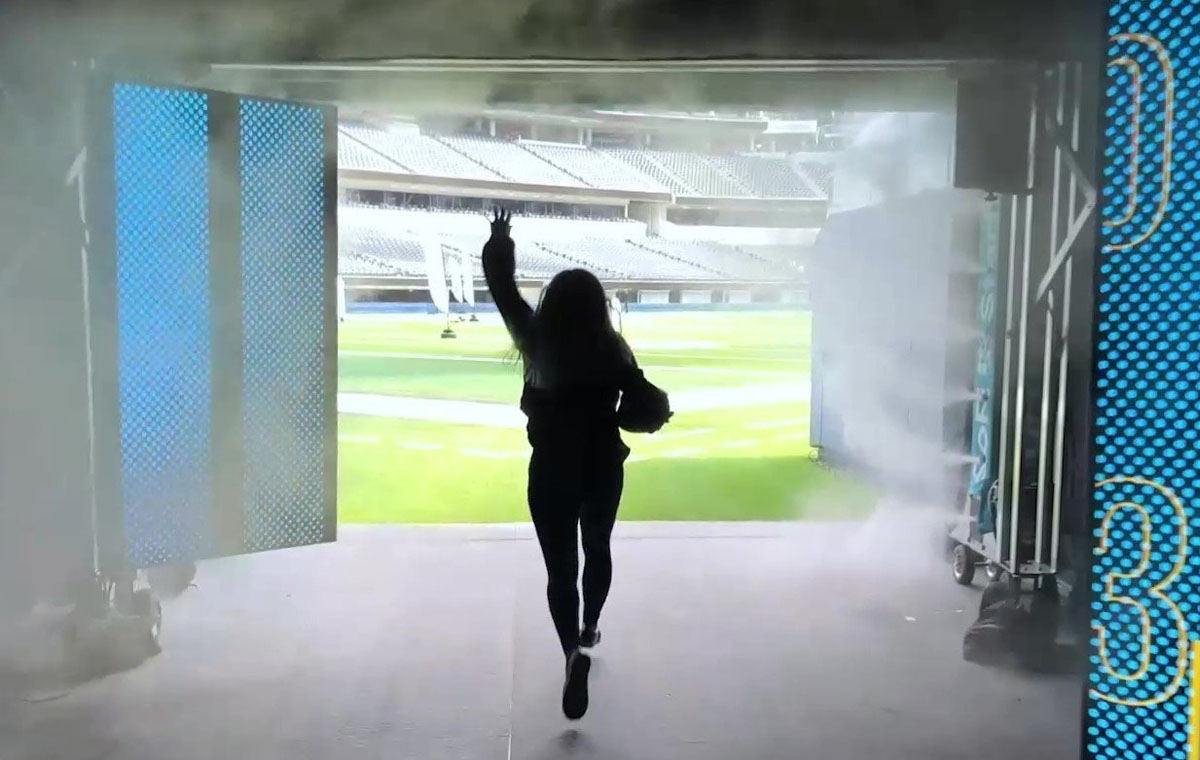 A woman running through an interactive technology tunnel at SoFi Stadium