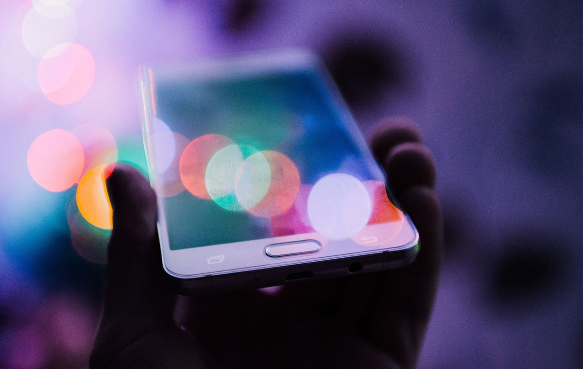 A man holding a mobile phone reflecting colored light as an example of digital wayfinding